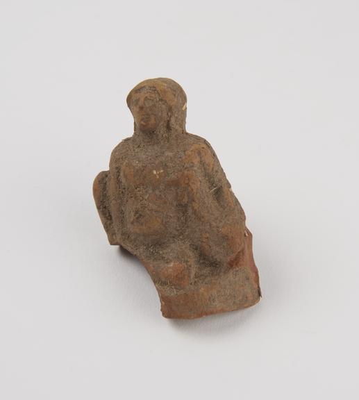 Votive statue of man sitting cross legged holding a bird under