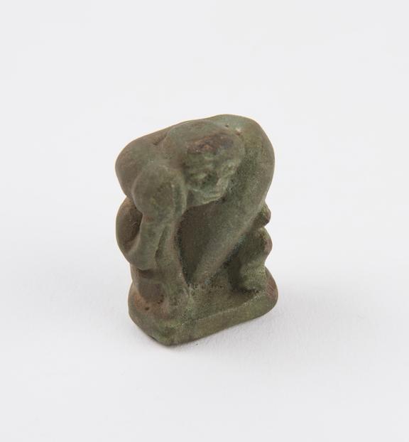 Glazed green faience pendant in form of seated phallic figure