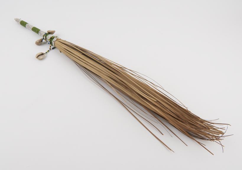 Palm leaf fly whisk with handle of beadwork and cowrie shells