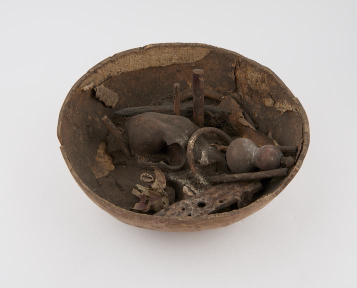 Hemispherical gourd bowl containing objects including bones and