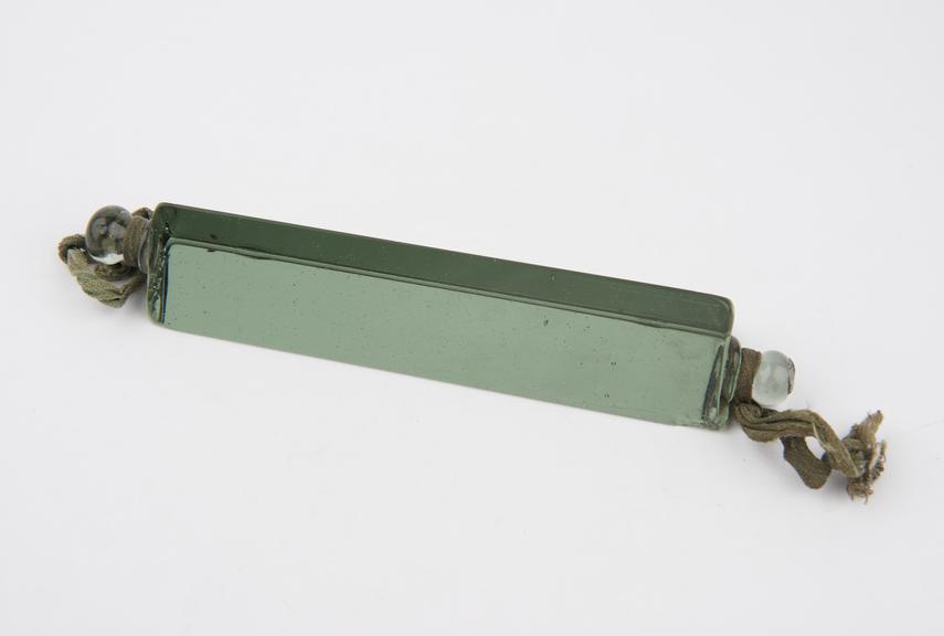 Green demonstration glass prism with cord attached to mounting