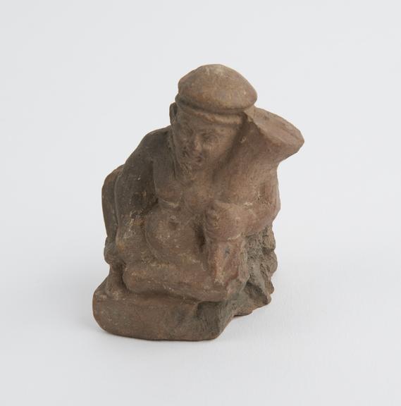 Small solid terracotta figure of phallic male holding a cornucopia probably Roman