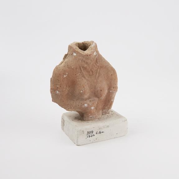 Statue of upper part of female, head missing, terracotta