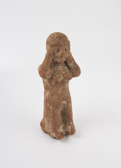 Solid terracotta figure of female with hands pressed to ears