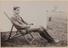 A man seated in a deck chair at a camp