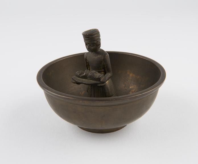 Small brass bowl with a figure holding a baby fixed to the base