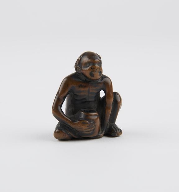 Wooden netsuke, in the form of a seated man holding a jar