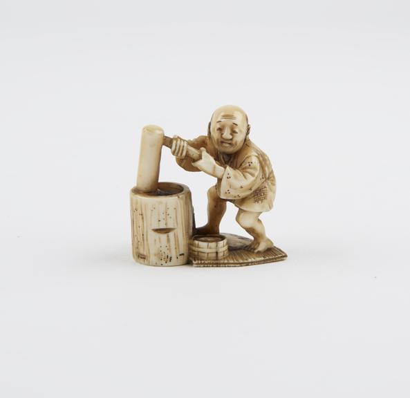 Ivory netsuke in the form of a man grinding with a mortar and