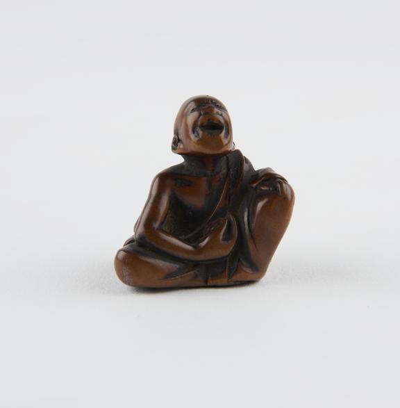 Wooden netsuke, in the form of a man seated cross-legged