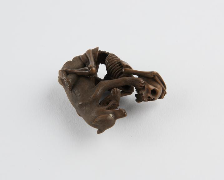 Wooden netsuke, in the form of a wolf fighting a skeleton