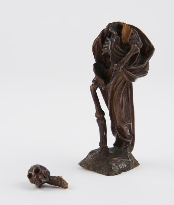 Wooden statue of a skeleton with a cloak around it