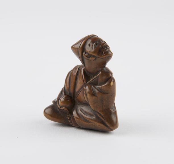 Wooden netsuke, in the form of a sitting man with a mask on