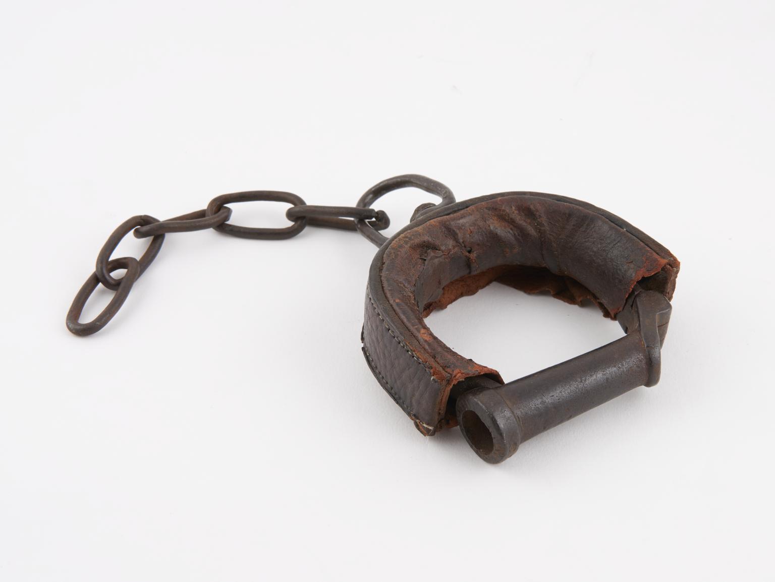 Replica of an iron wrist restrainer covered in leather. The original