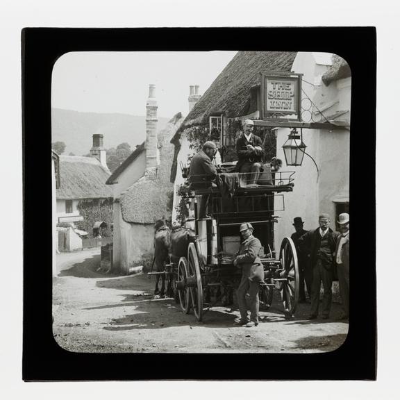 A magic lantern slide showing Birt Acres sitting on a coach