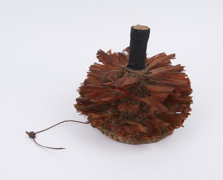 Headdress, cone shaped straw hat decorated with red feathers