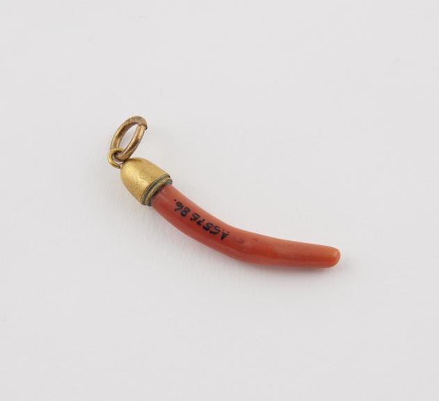 Piece of coral brass mounted at end with ring for suspension