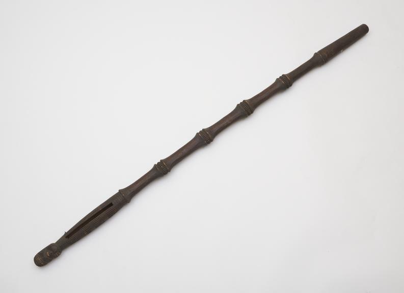 Carved wooden staff with rattle at top