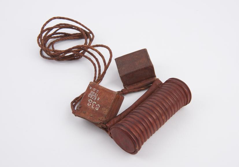 Three red leather amulet cases attached to plaited leather