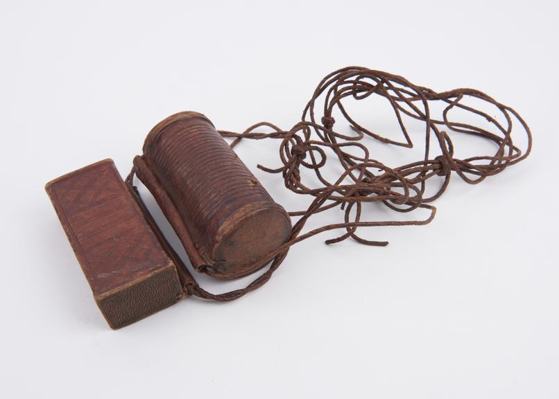 Pair of leather covered amulet cases on long sling containing extracts of Koran