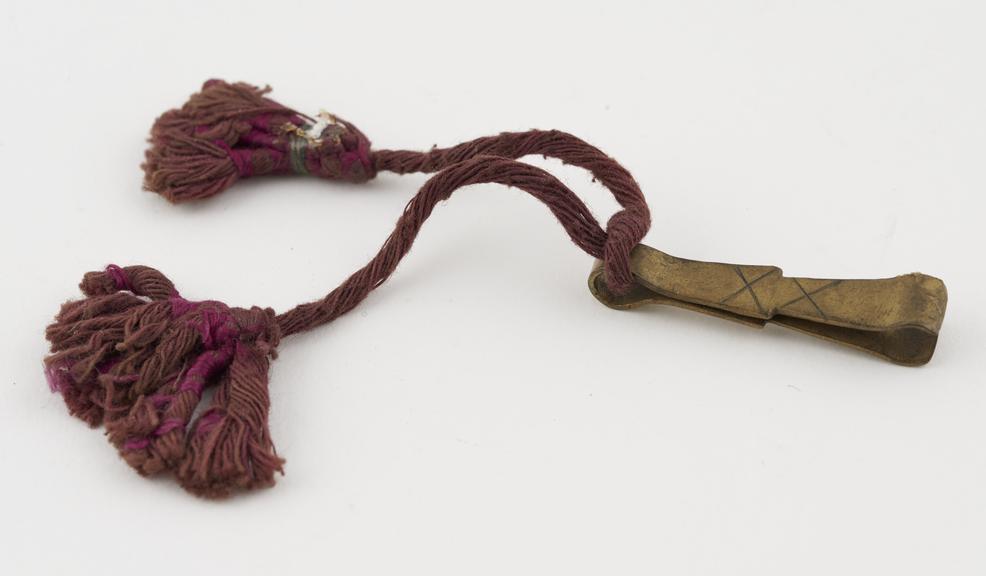 Brass depilatory tweezers, on purple fibre string