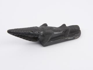 Black earthenware skin scraper in form of crocodile