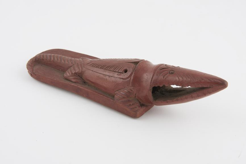 Red earthenware skin scraper in form of crocodile