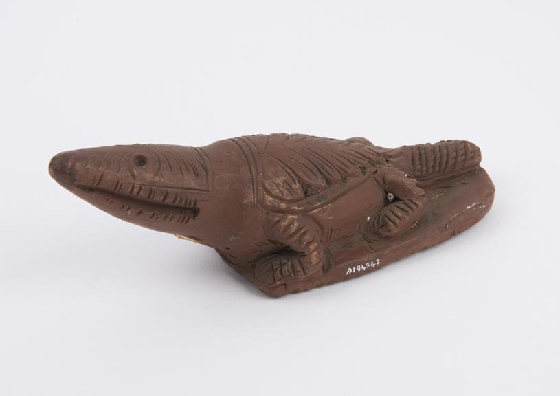 Red earthenware skin scraper in form of crocodile