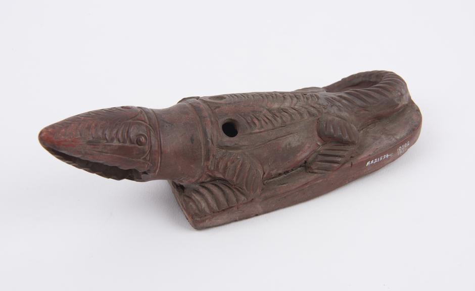 Red earthenware skin scraper in form of crocodile with rasp base