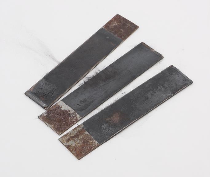 Three steel strips, partially coated with unknown material
