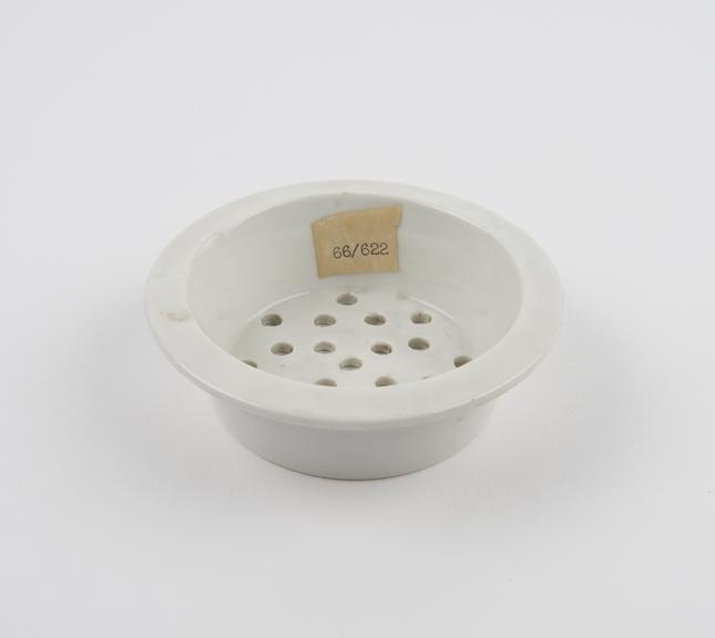 Circular white earthenware sieve from food warmer