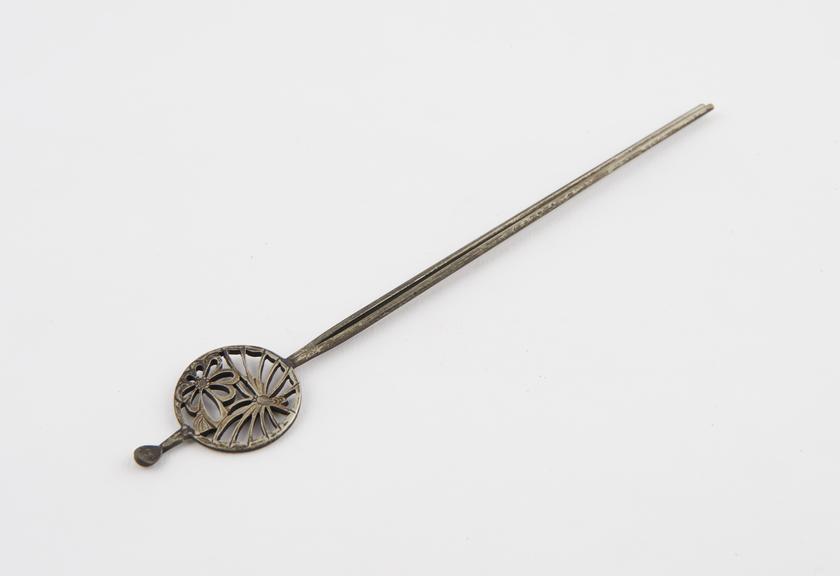 Double-pronged metal hair pin with circular finial which has