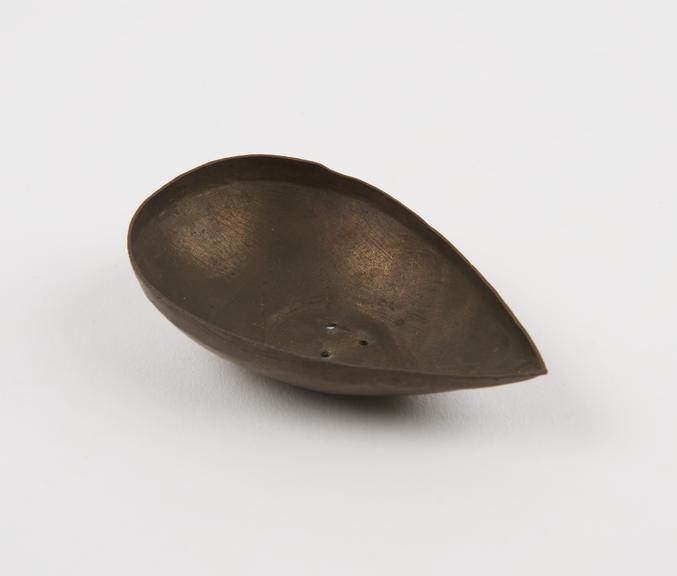 Brass pap boat with holes punched in bottom for use as strainer