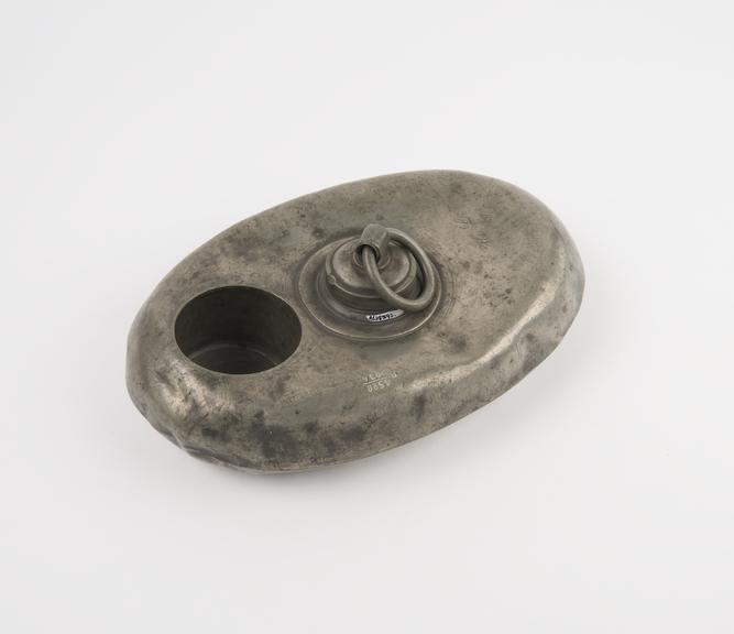 Oval pewter hot water bottle with ring handled screw cap in