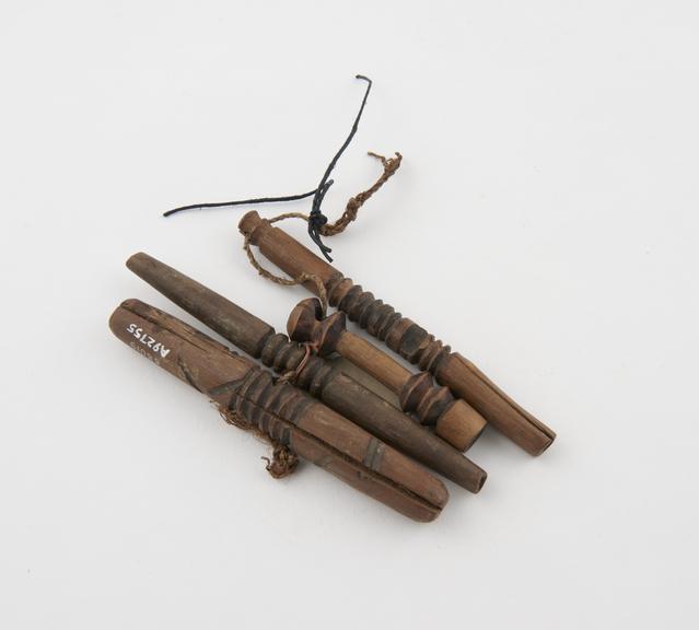 Four pegs of carved wood threaded together onto string