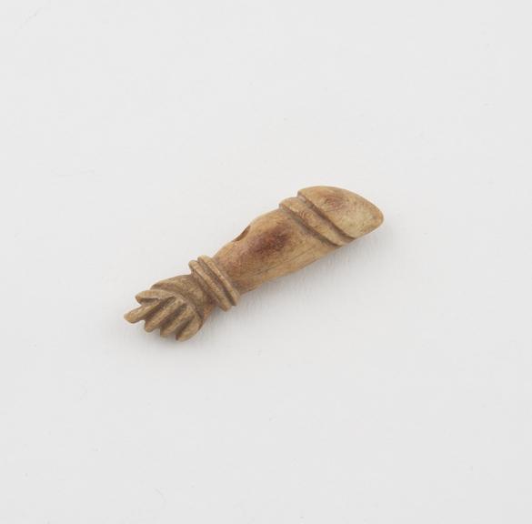 Amuletic pendant of carved ivory in form of arm with phallus