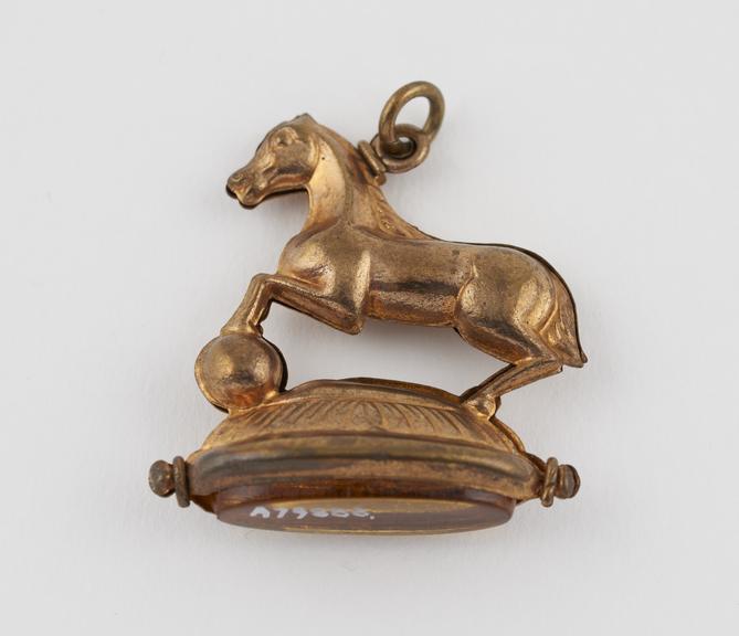 Amulet, metal, gilt, horse on oval base