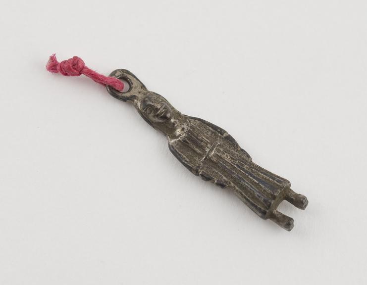 Small silver(?) pendant in form of figure in long tunic