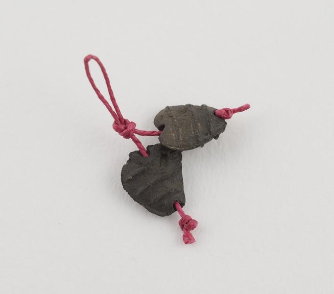 Pair of black metal(?) beads, amuletic, heart-shaped and ribbed
