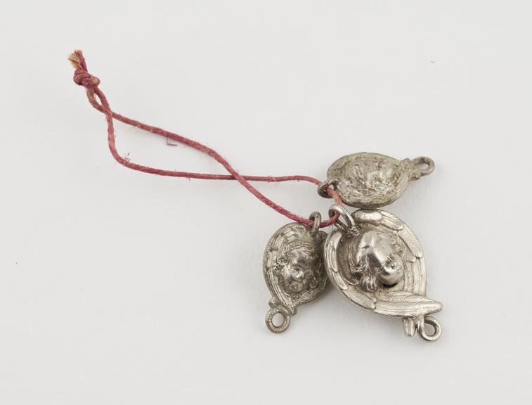 3 amuletic pendants made of silvery metal in form of angel's