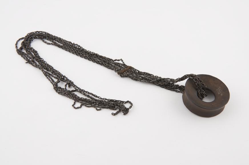 Decorative ear distender of wood with suspended metal chain