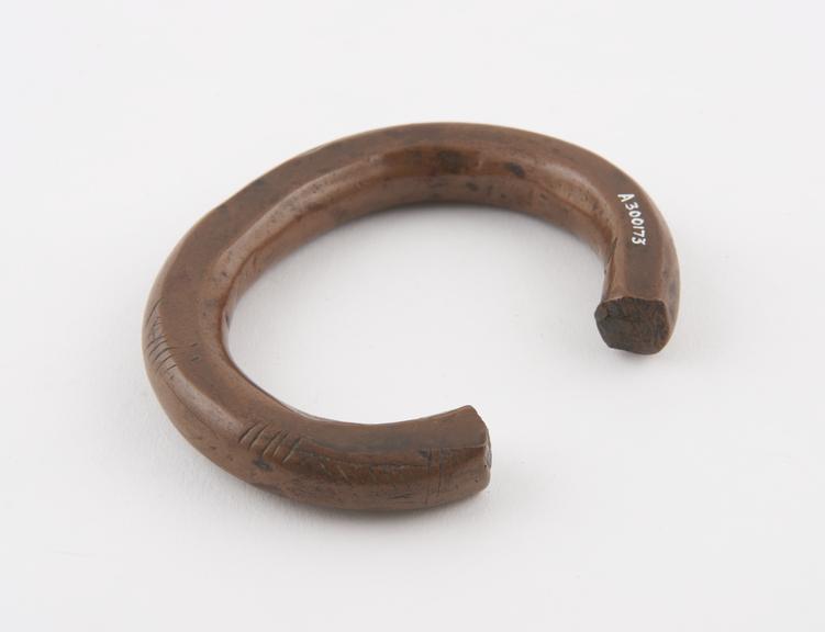 Copper anklet, pennancular with roughly incised decoration