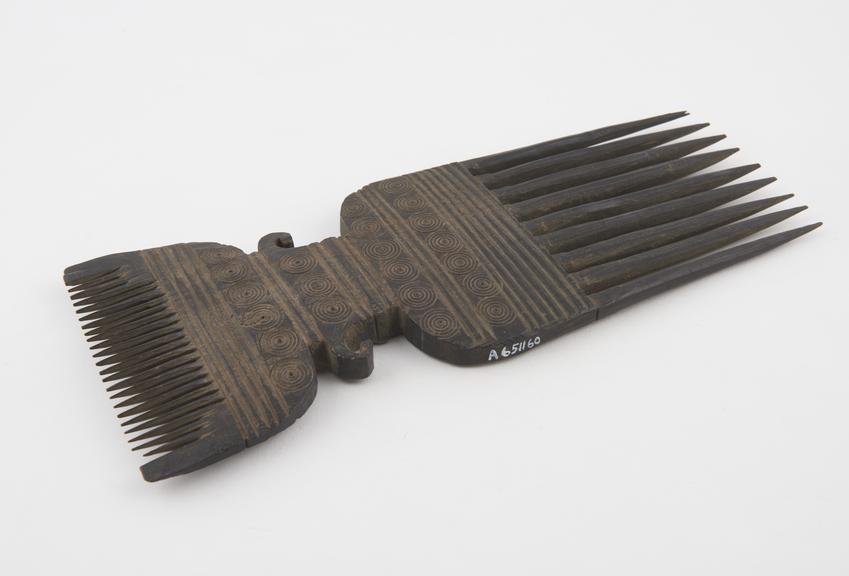 Double-pronged comb of hard black wood with carved middle