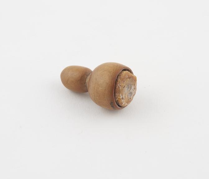 Acorn-shaped wooden ear ornament, filled with cow's fat