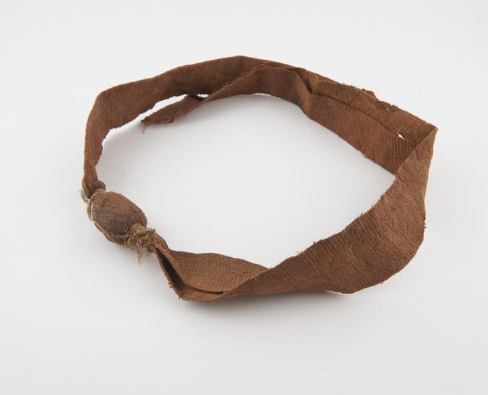 Belt made of bark cloth with amuletic object sewn into centre