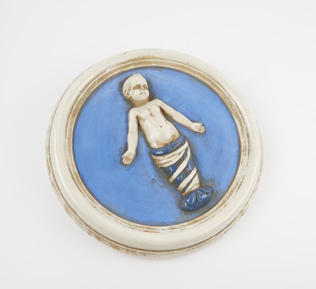 Circular porcelain plaque depicting child in swaddling clothes