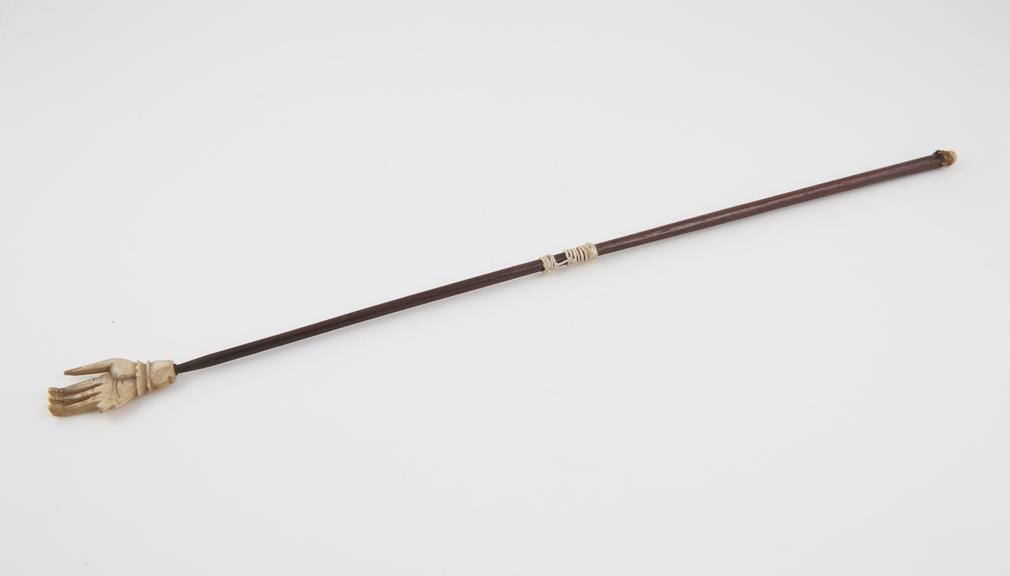 Wood-handled ivory back scratcher, in from of a hand