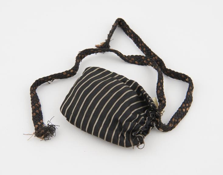 Number of animal teeth in black and white striped silk bag with