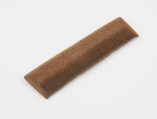 Close toothed wooden comb with simple carved design on handle