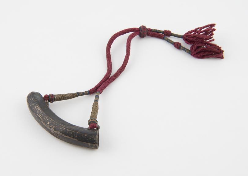 Amuletic case, silver, in shape of banana suspended on red cord