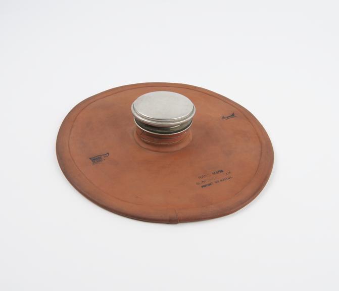 Circular rubber hot water bottle with metal filler cap in